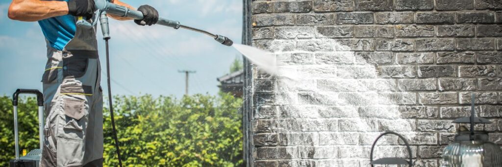 A man soft washing brick siding